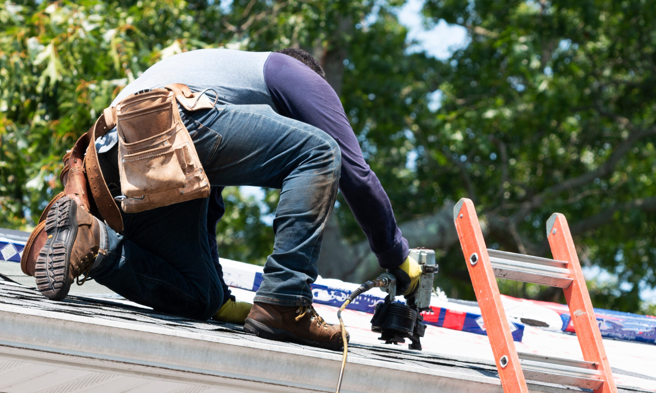 Roofer nailing shingles during a roof replacement
