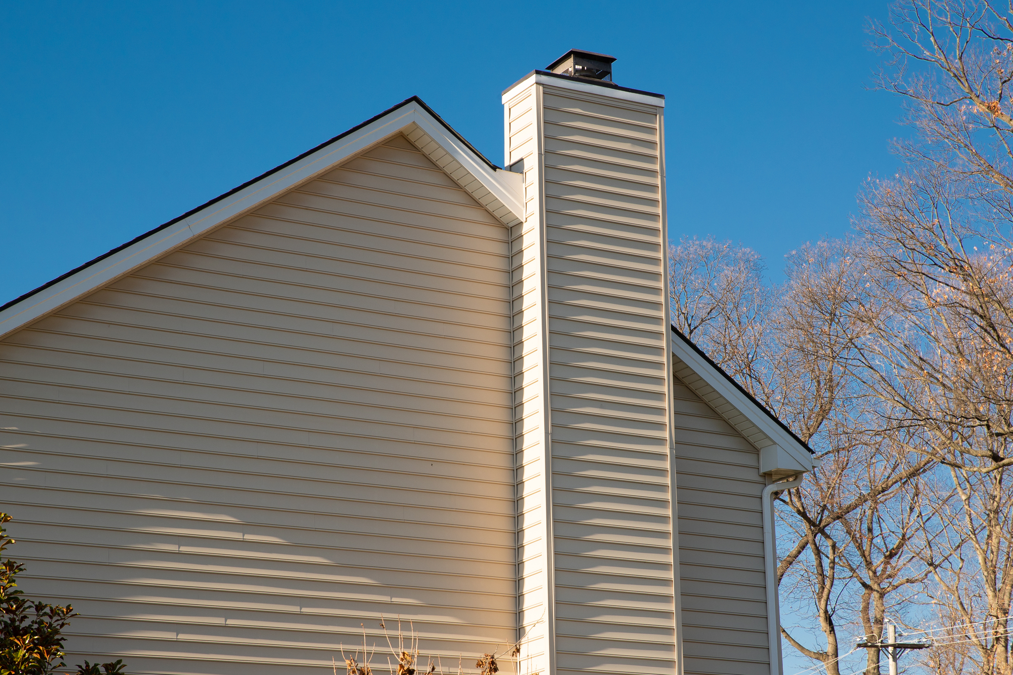 Yellow siding on the side of a house with a chimney