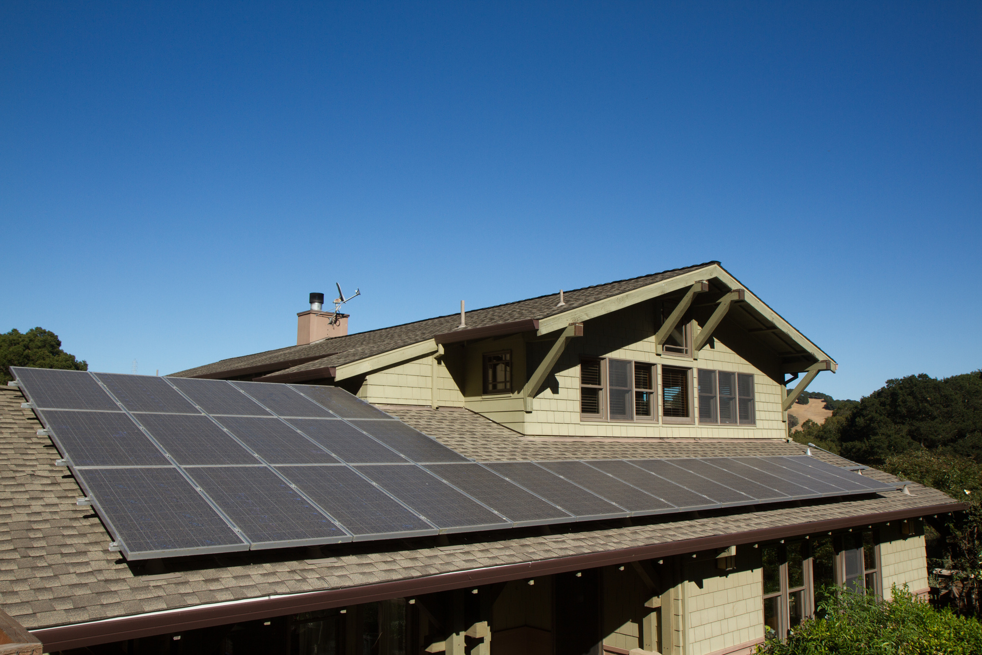 Solar panels on a brown asphalt shingle roof and a brown house