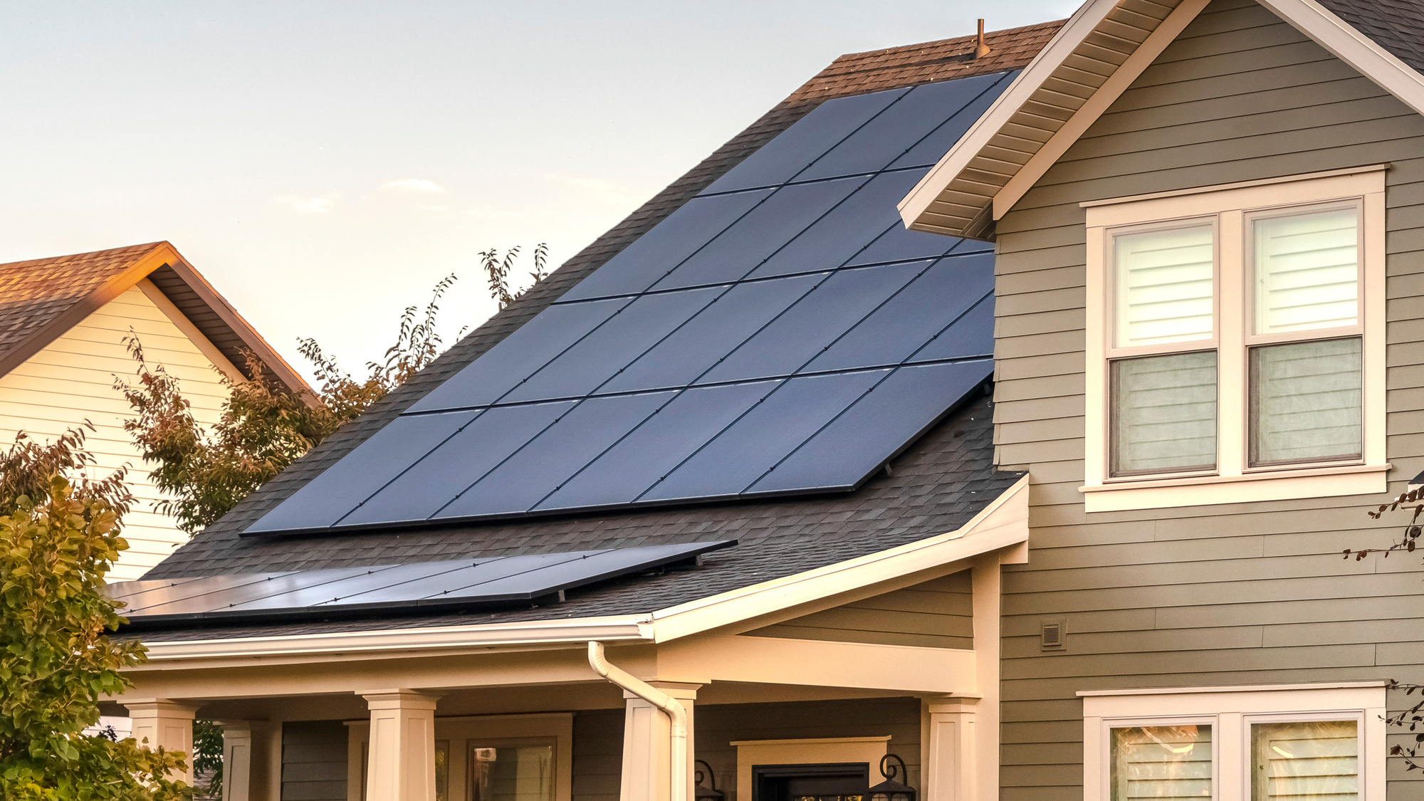 Solar panels on a shingle roof and a tan house