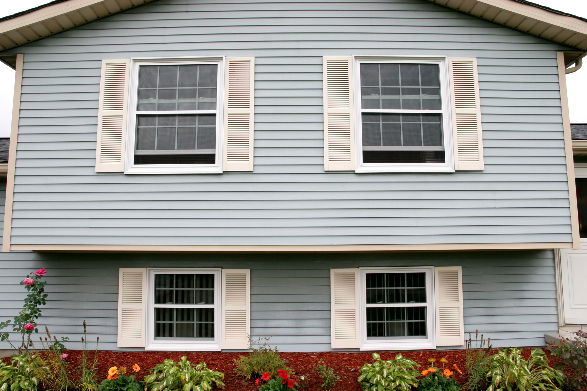 Blue siding on a two-story house with four large windows