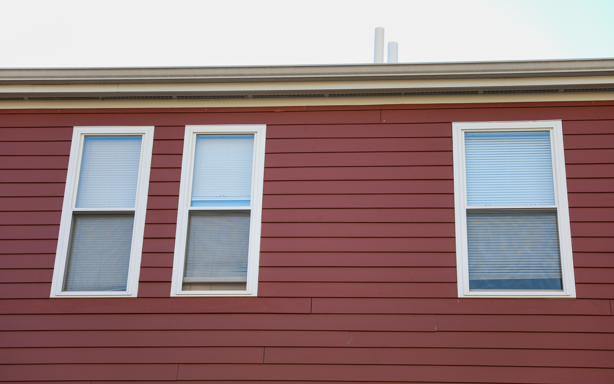 Red siding on a house with three vertical windows