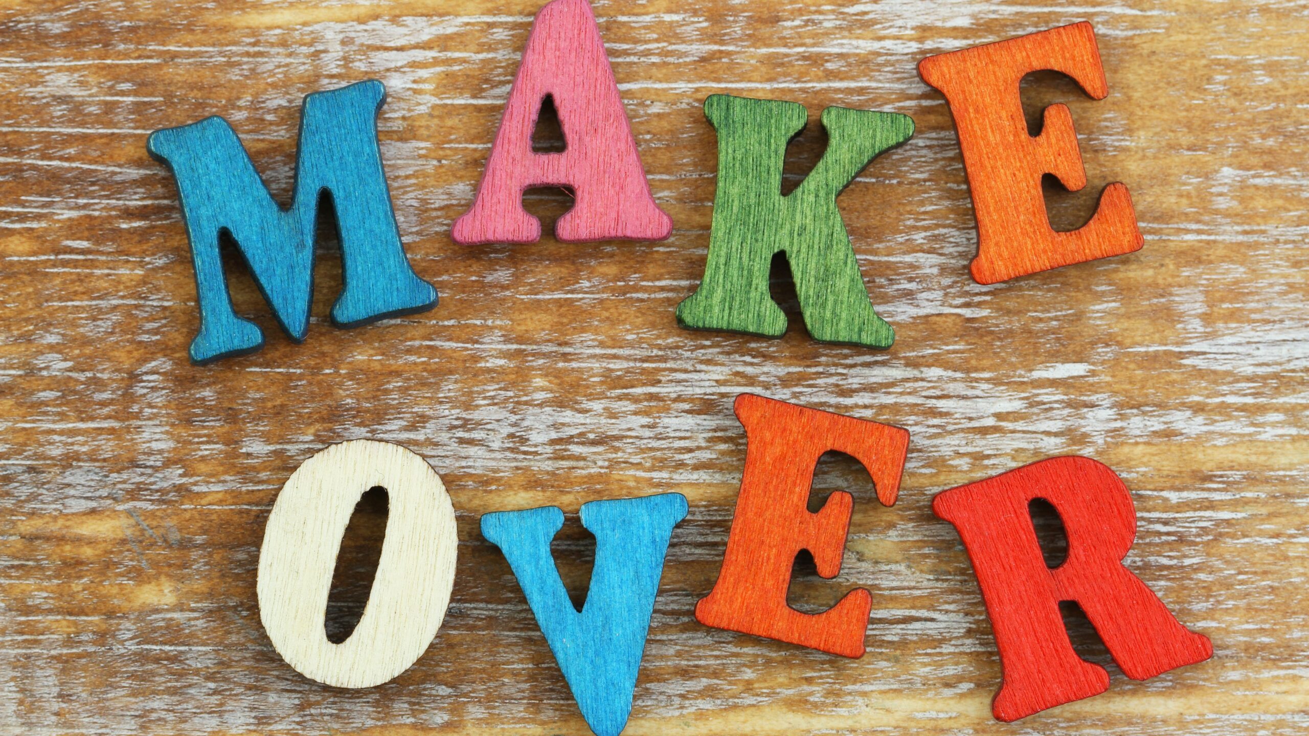 The word “Makeover” is written with colorful wooden letters on a rustic surface.