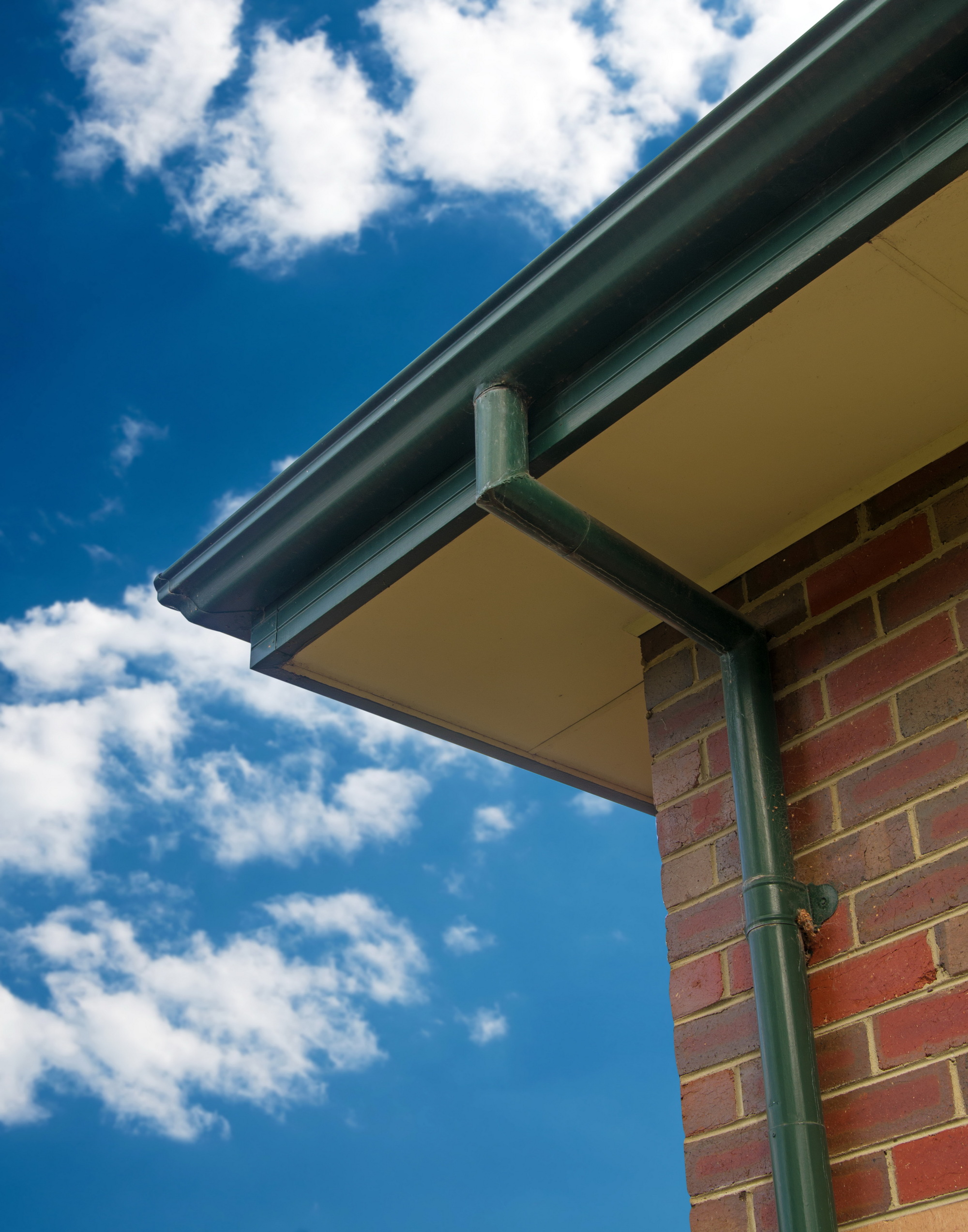 Angled view of green gutters on brick house