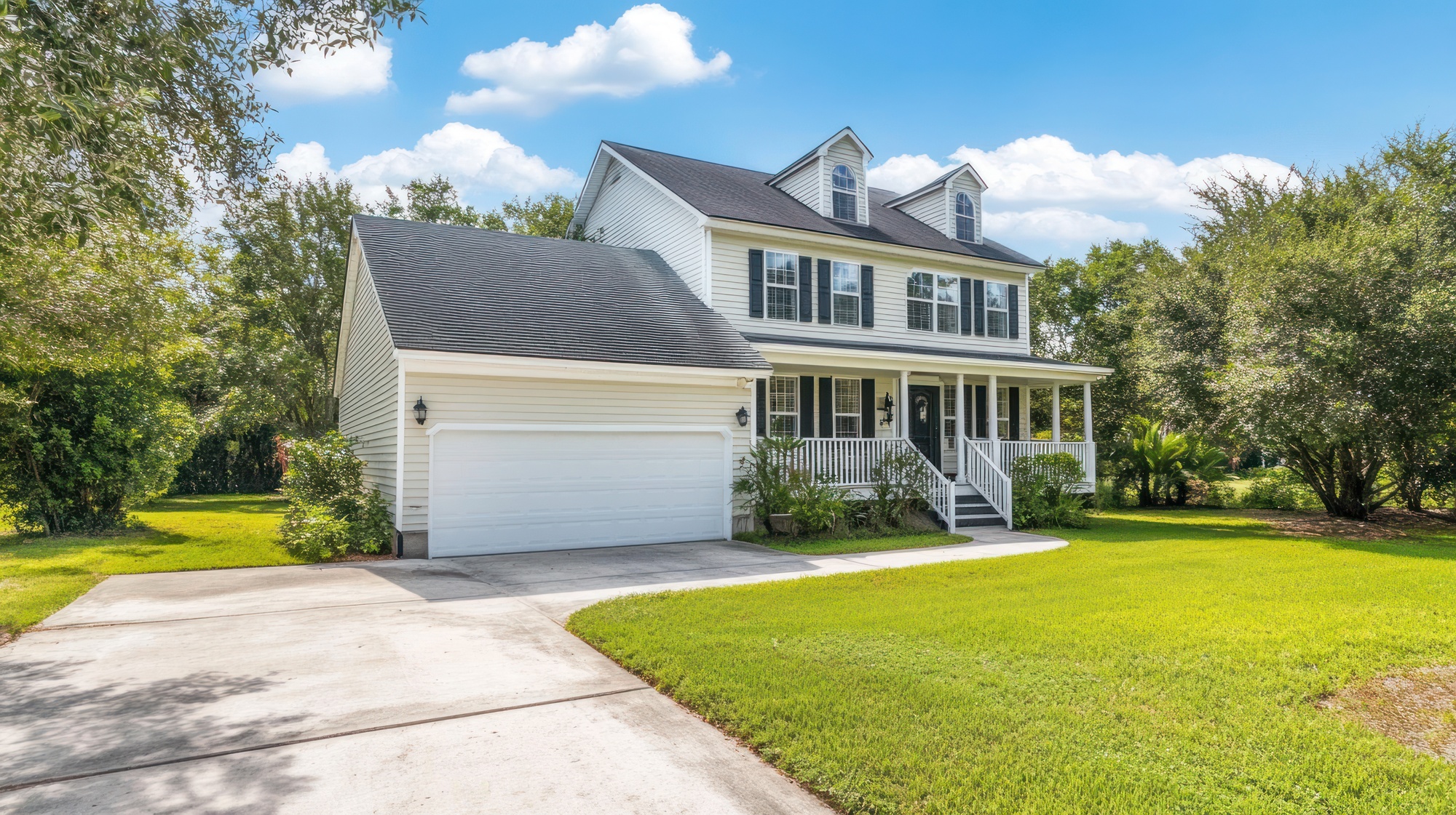 Large white house with an asphalt shingle roof, a white garage door, and a front porch