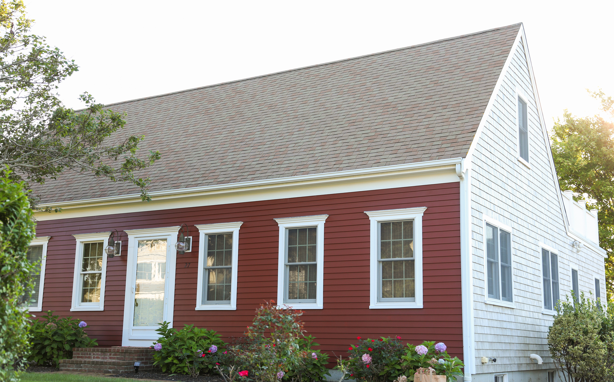 Asphalt shingle roof on a red house with white windows
