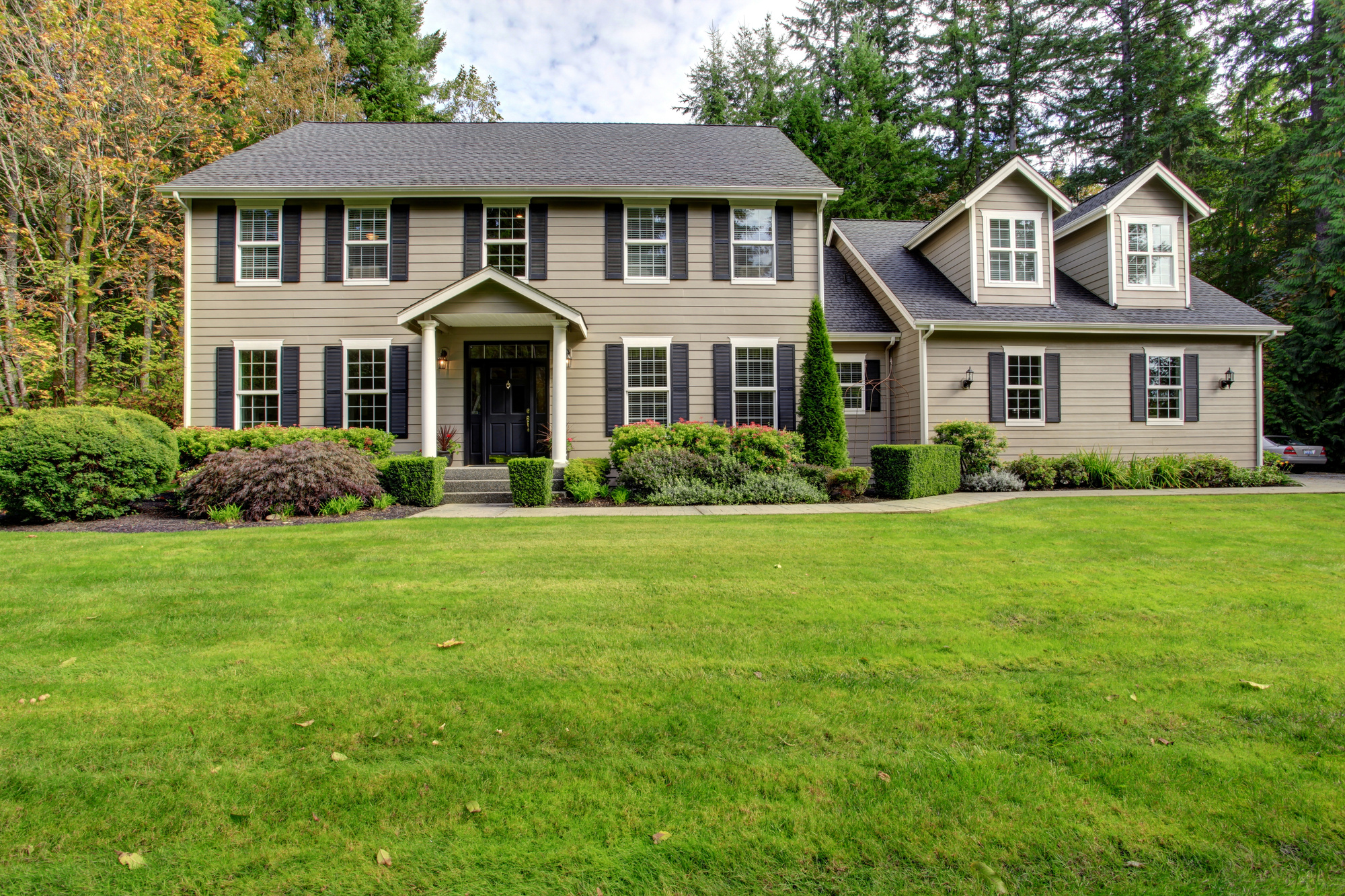 Two-story brown house with a black door and several windows