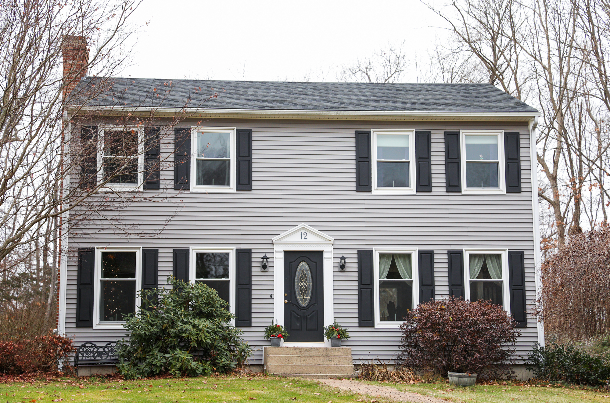 Two-story house with eight windows, a black door, and a shingle roof