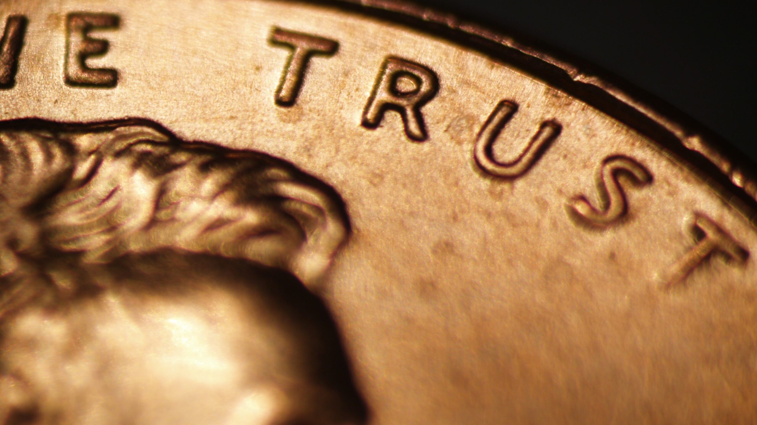The top of a penny with a close-up on the word “trust.”