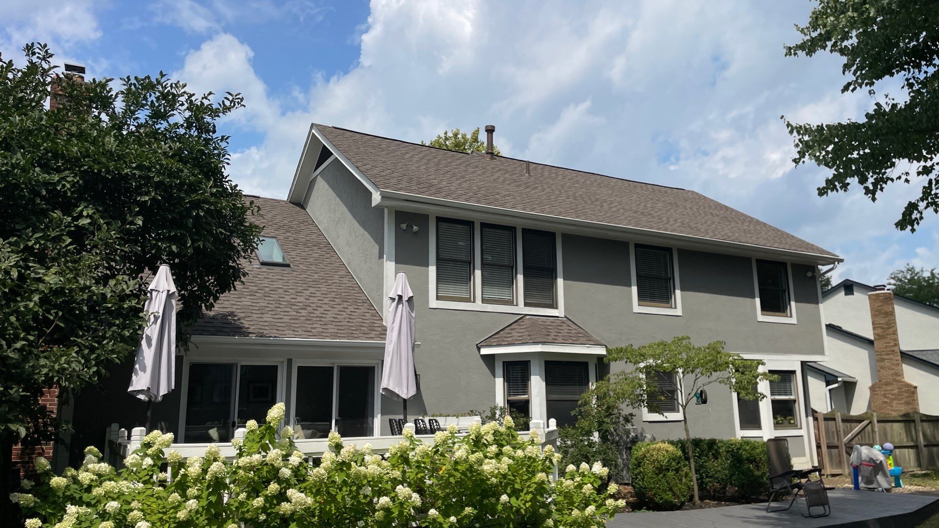 A brown asphalt roof installed on a gray home