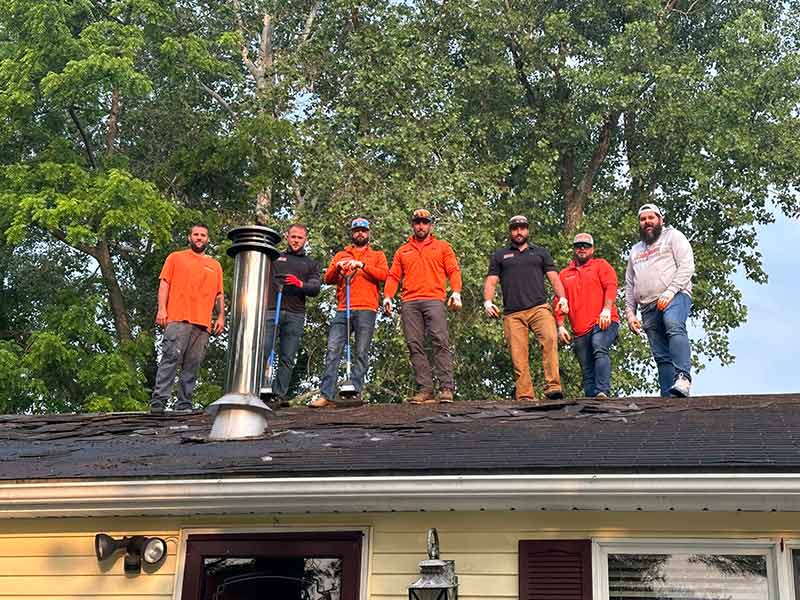 BCS Roofing team members posing for a picture on a residential roof they are working on
